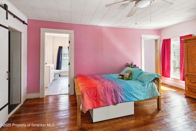 bedroom featuring a barn door, a ceiling fan, and hardwood / wood-style flooring
