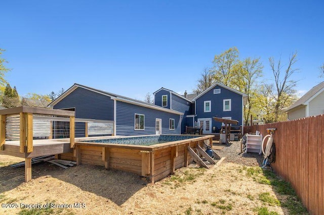 back of house with fence, a wooden deck, and a fenced in pool