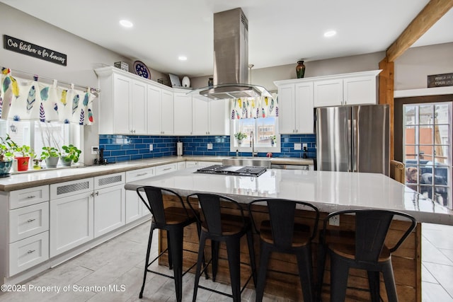kitchen featuring island exhaust hood, decorative backsplash, stainless steel appliances, and white cabinets