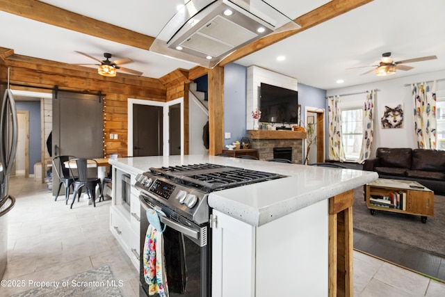 kitchen featuring stainless steel gas range oven, white cabinets, open floor plan, and ceiling fan
