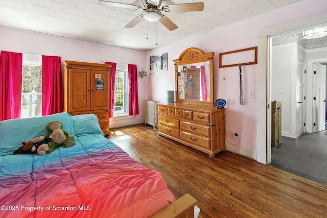 bedroom with radiator, wood finished floors, and ceiling fan
