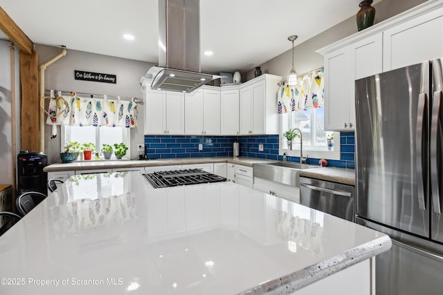 kitchen with tasteful backsplash, a sink, island exhaust hood, white cabinets, and appliances with stainless steel finishes
