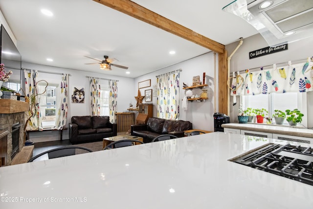 kitchen with ceiling fan, a stone fireplace, light countertops, and recessed lighting