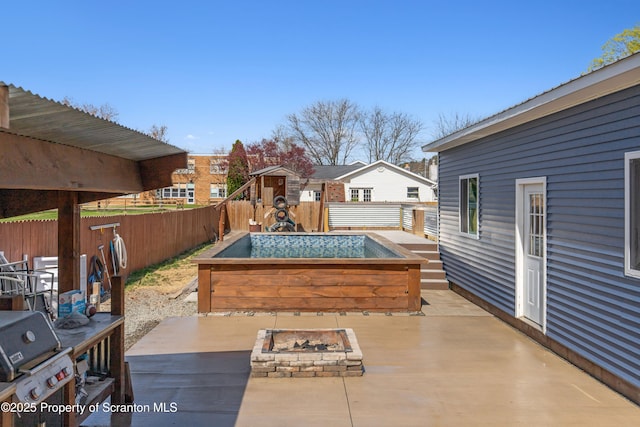 view of patio with a fenced backyard, a wooden deck, an outdoor fire pit, and grilling area