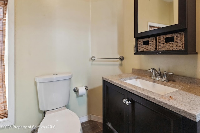 bathroom with toilet, vanity, tile patterned floors, and baseboards