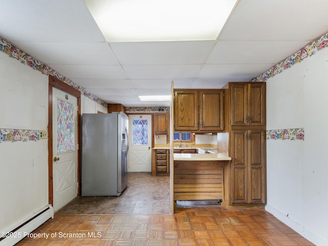 kitchen with a paneled ceiling, stainless steel fridge, light parquet floors, baseboard heating, and kitchen peninsula