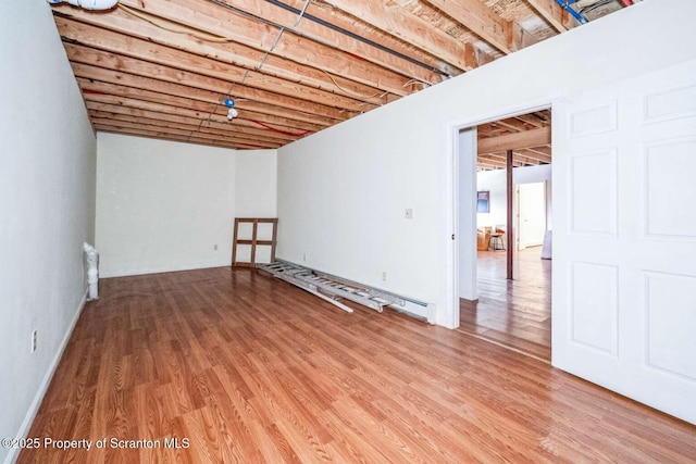 basement with hardwood / wood-style floors and baseboard heating