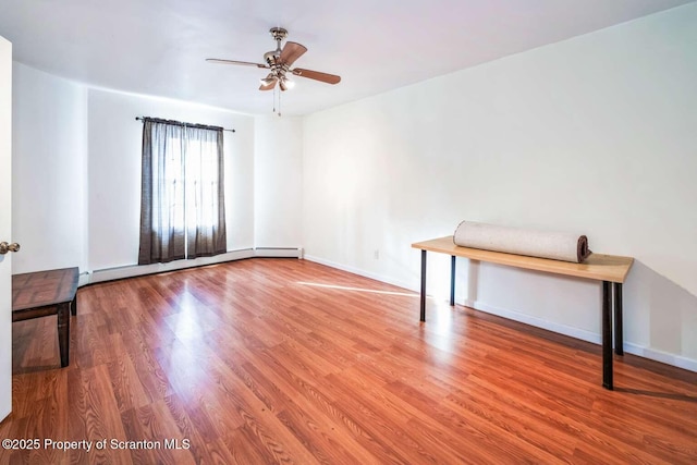 spare room with wood-type flooring, a baseboard heating unit, and ceiling fan