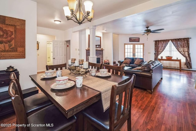 dining area with ceiling fan with notable chandelier, dark hardwood / wood-style flooring, and decorative columns