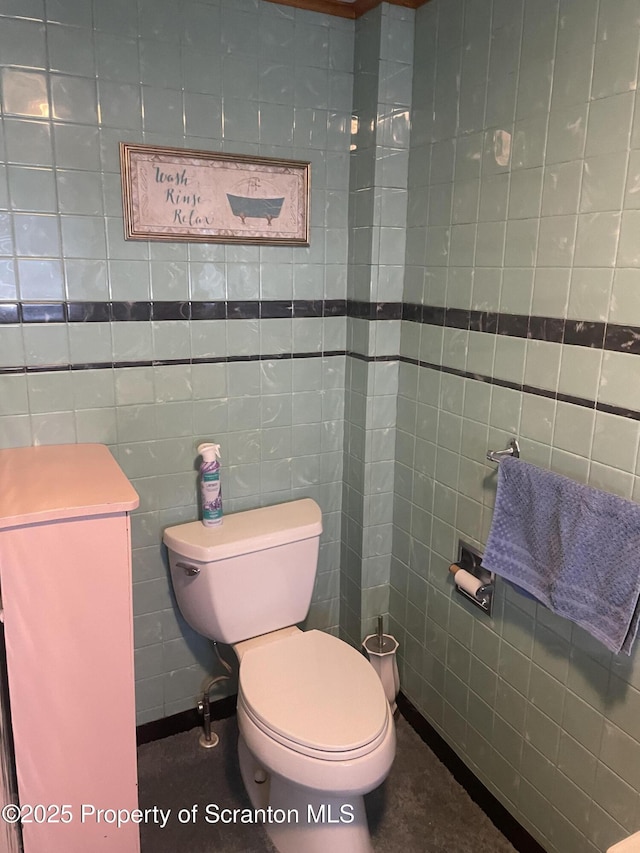 bathroom featuring toilet and tile walls