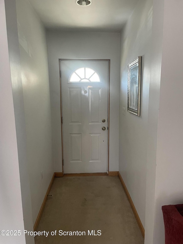 doorway with baseboards and light colored carpet