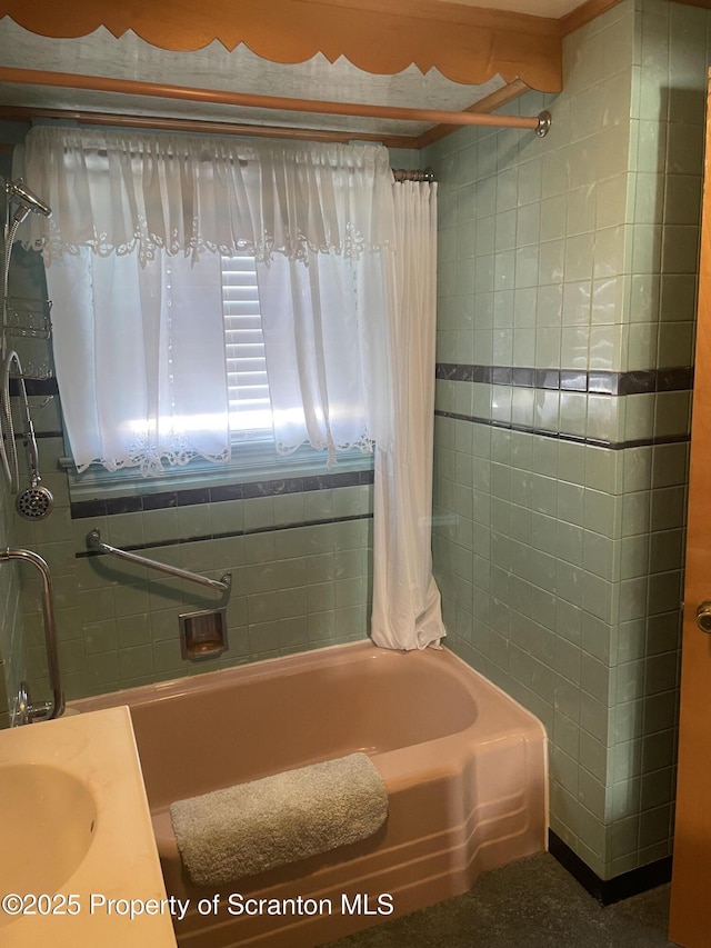 bathroom featuring shower / tub combo with curtain, tile walls, and a sink