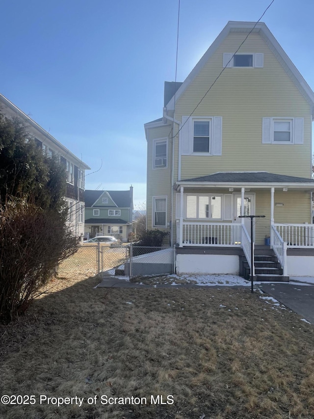 rear view of house with a porch and fence