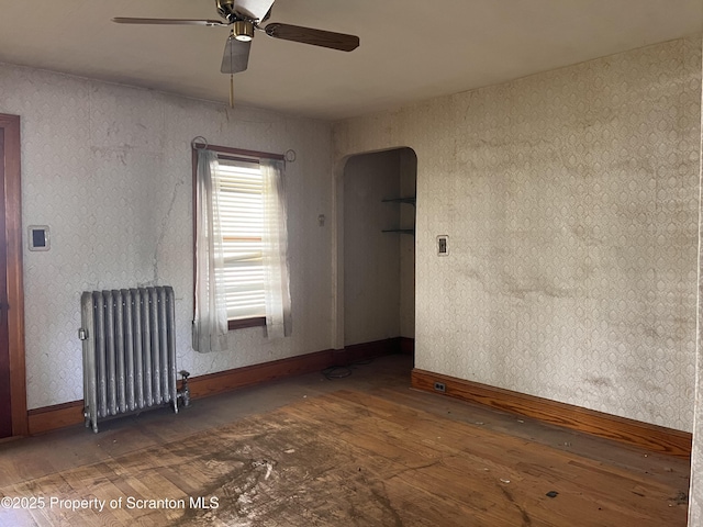 826 N Main St, Forest City, PA 18421 - unfurnished room featuring radiator, wood-type flooring, a ceiling fan, and arched walkways
