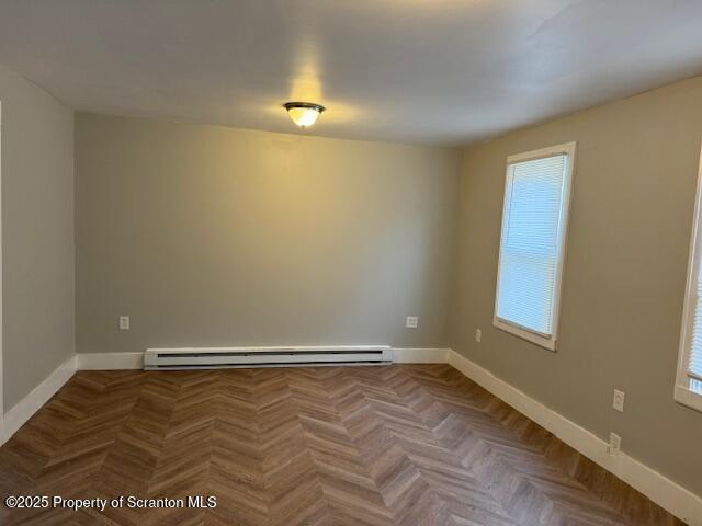 unfurnished room featuring parquet floors and a baseboard radiator