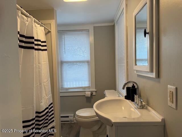 bathroom with walk in shower, ornamental molding, a baseboard heating unit, sink, and toilet