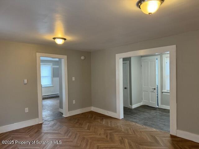 spare room with dark parquet floors and baseboard heating