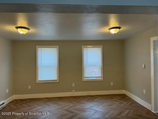 spare room featuring a baseboard heating unit and parquet flooring