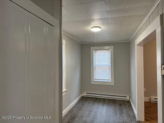 spare room with ornamental molding, dark wood-type flooring, and a baseboard radiator