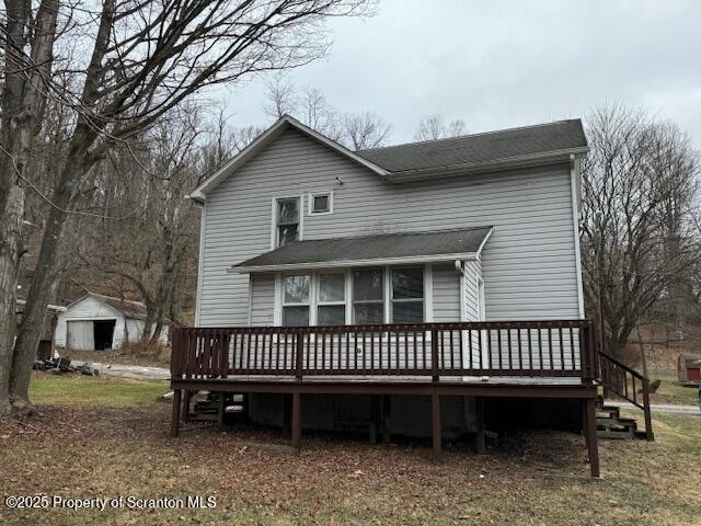 rear view of property featuring a deck and a storage shed