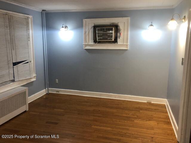 spare room featuring crown molding, dark hardwood / wood-style flooring, and radiator