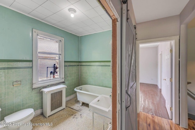 1725 Cedar Ave, Scranton, PA 18505 - full bathroom featuring radiator heating unit, tile walls, a freestanding tub, and a wainscoted wall