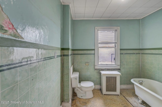 1725 Cedar Ave, Scranton, PA 18505 - full bathroom with a soaking tub, radiator heating unit, tile walls, speckle patterned floor, and wainscoting
