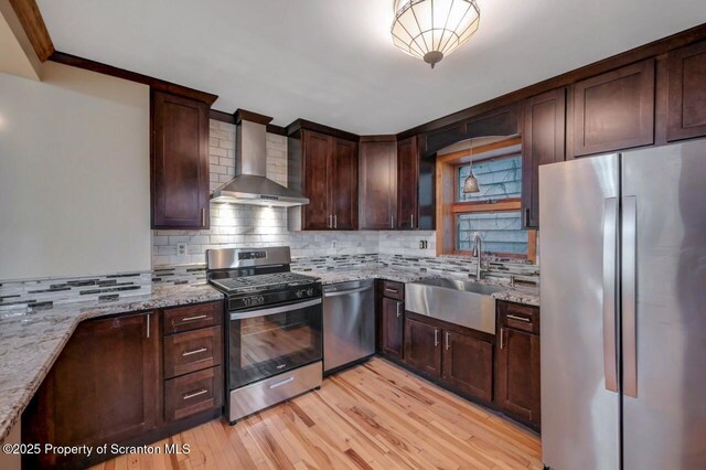 1725 Cedar Ave, Scranton, PA 18505 - kitchen with stainless steel appliances, wall chimney exhaust hood, backsplash, light stone counters, and light wood-style flooring