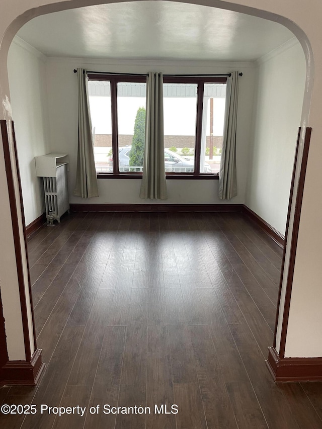 809 Cedar Ave, Scranton, PA 18505 - unfurnished living room featuring arched walkways, radiator, healthy amount of natural light, and crown molding