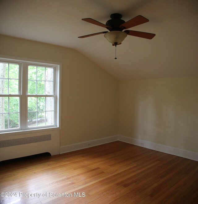 bonus room featuring a ceiling fan, vaulted ceiling, light wood-type flooring, baseboards, and radiator