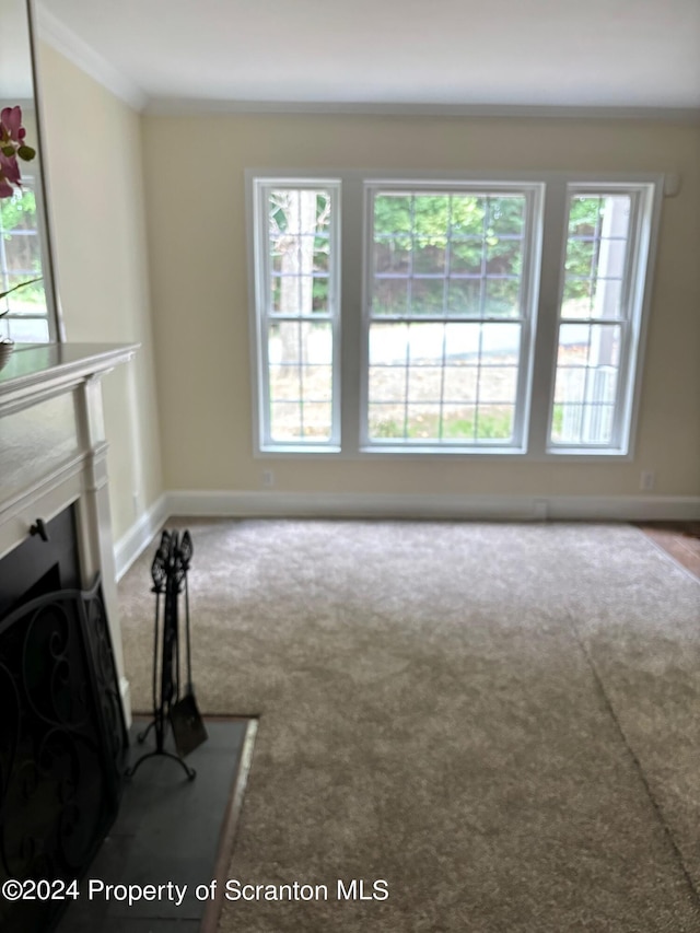 unfurnished living room with crown molding, carpet floors, and baseboards