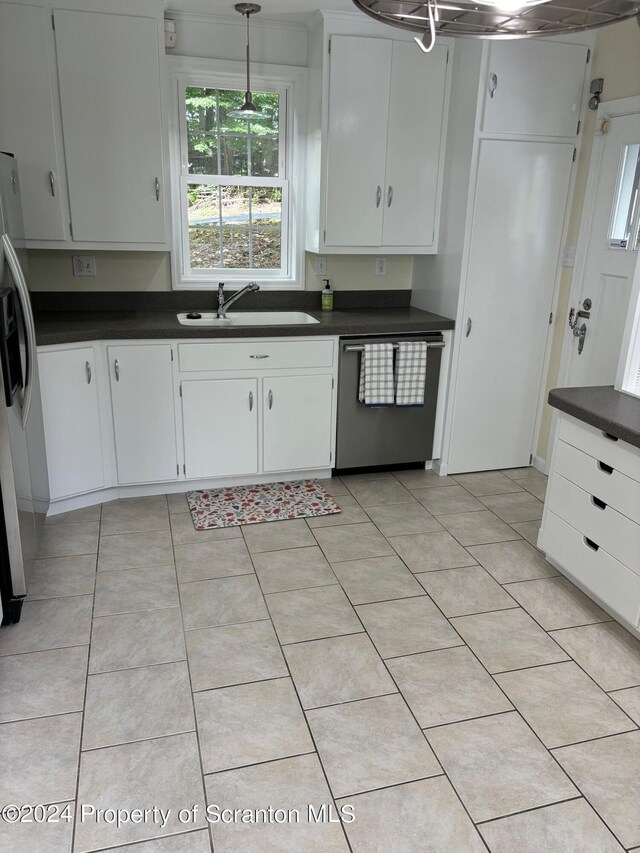 kitchen with white cabinets, dark countertops, appliances with stainless steel finishes, a sink, and pendant lighting