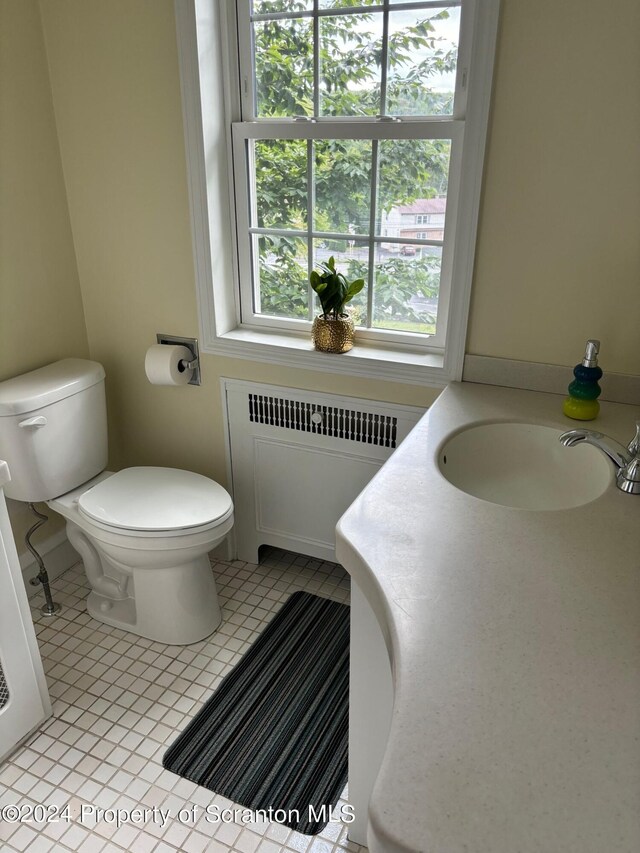 bathroom with radiator heating unit, tile patterned flooring, toilet, and a sink