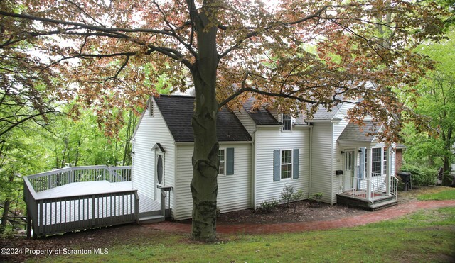 back of property with roof with shingles and a wooden deck