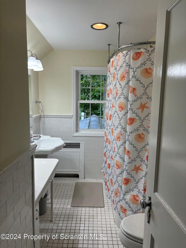 bathroom featuring tile patterned flooring, toilet, radiator, tile walls, and curtained shower