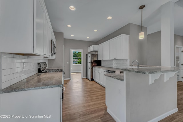 98 Electric St Unit L 1, Clarks Summit, PA 18411 - kitchen with appliances with stainless steel finishes, a peninsula, light wood-type flooring, white cabinets, and a kitchen bar