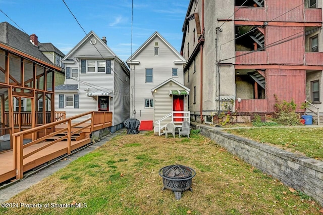 rear view of house with an outdoor fire pit, a lawn, and a wooden deck