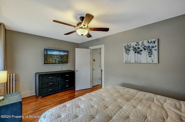 bedroom with hardwood / wood-style floors, ceiling fan, and radiator heating unit