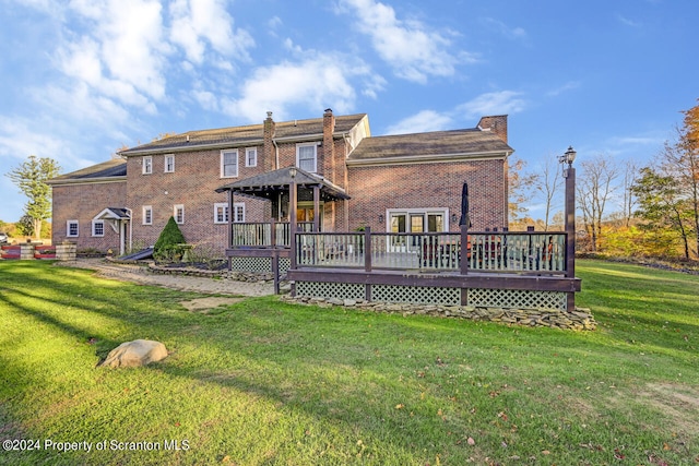 rear view of property with a yard and a wooden deck