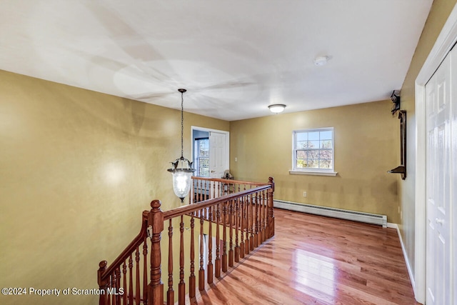 stairs featuring hardwood / wood-style flooring and a baseboard heating unit