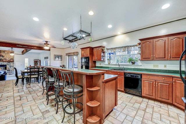 kitchen featuring a kitchen bar, ceiling fan, sink, black appliances, and a kitchen island