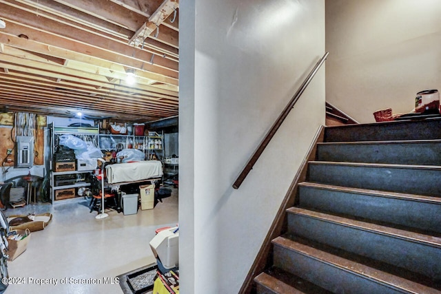 stairs featuring concrete flooring and electric panel