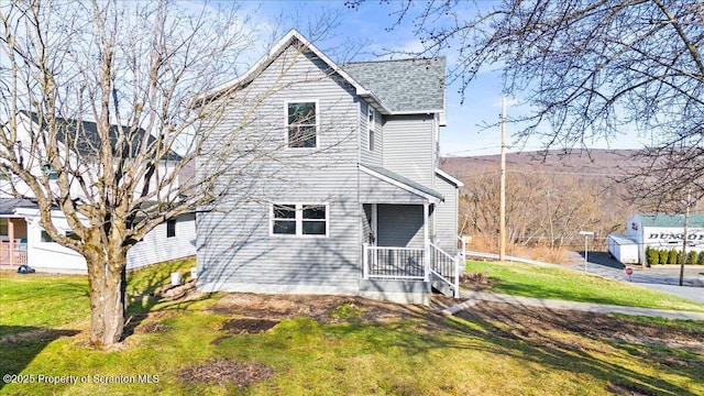 view of front of property with a shingled roof and a front lawn