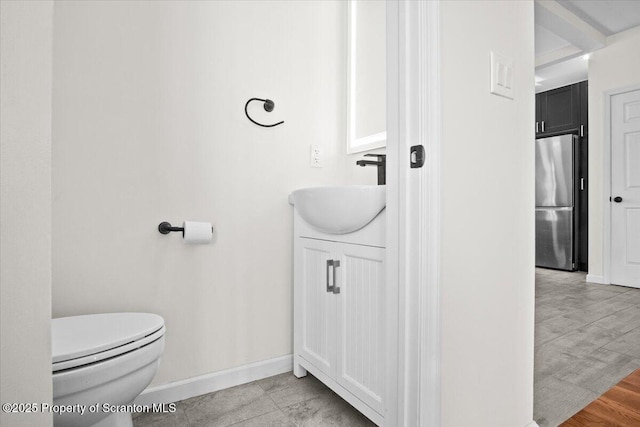 bathroom featuring toilet, vanity, and baseboards