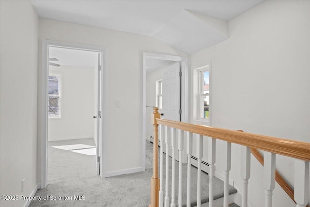 corridor with carpet flooring, an upstairs landing, baseboards, and a baseboard heating unit