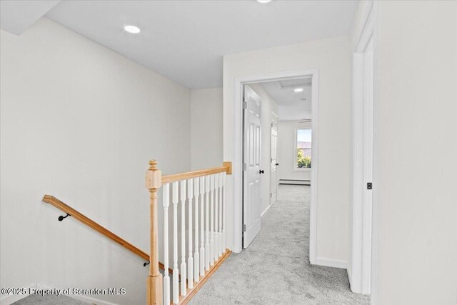 corridor with baseboards, carpet flooring, an upstairs landing, and baseboard heating