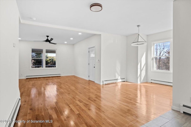 unfurnished living room with baseboard heating, wood finished floors, and a baseboard heating unit