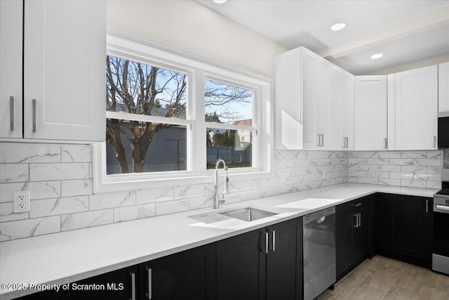 kitchen with white cabinetry, tasteful backsplash, stainless steel appliances, a sink, and dark cabinets
