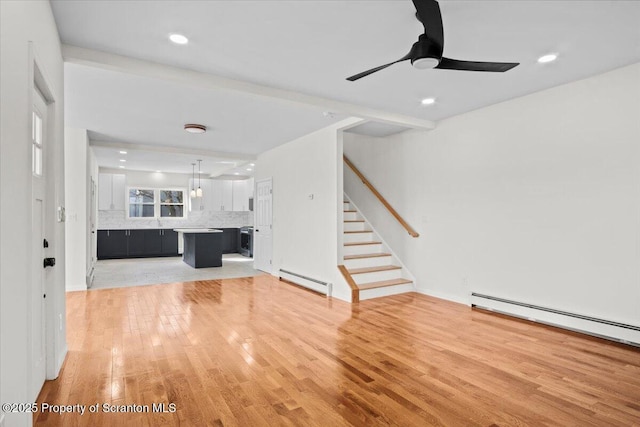 unfurnished living room with stairs, light wood finished floors, baseboard heating, a baseboard heating unit, and ceiling fan