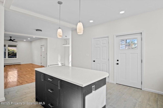 kitchen with light countertops, a kitchen island, baseboard heating, light wood-style floors, and dark cabinets